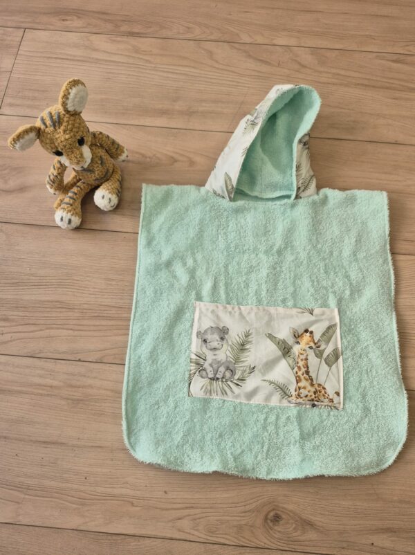 Poncho de bain pour enfant présenté avec la peluche lionceau , le poncho est en tissu éponge de couleur verte et un coton imprimé animaux.